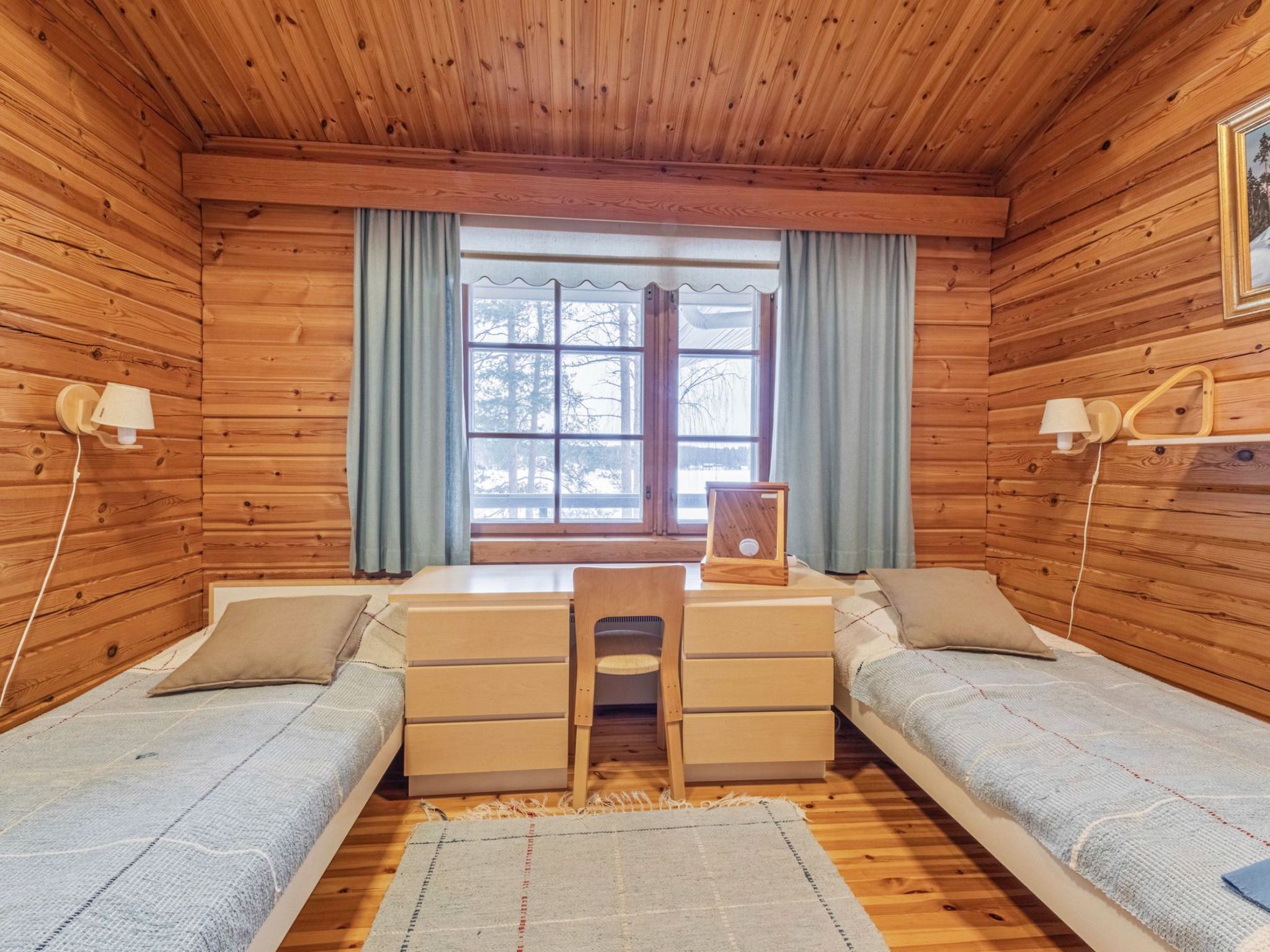 Een knus kamer in een chalet met twee bedden, een bureau en een raam met gordijnen.