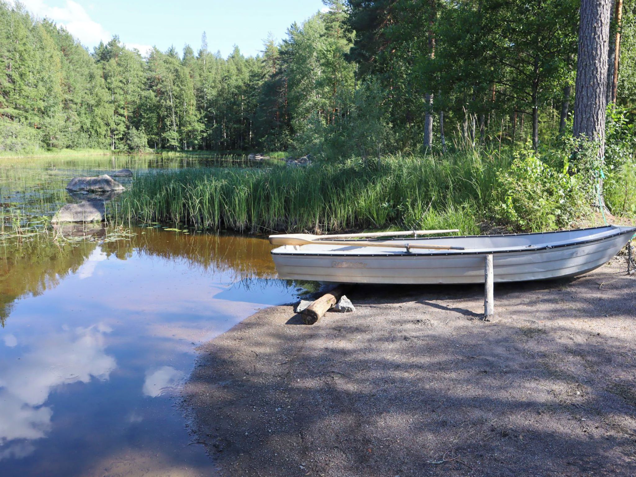 A boat tied to a dock by a calm lake surrounded by dense forest.