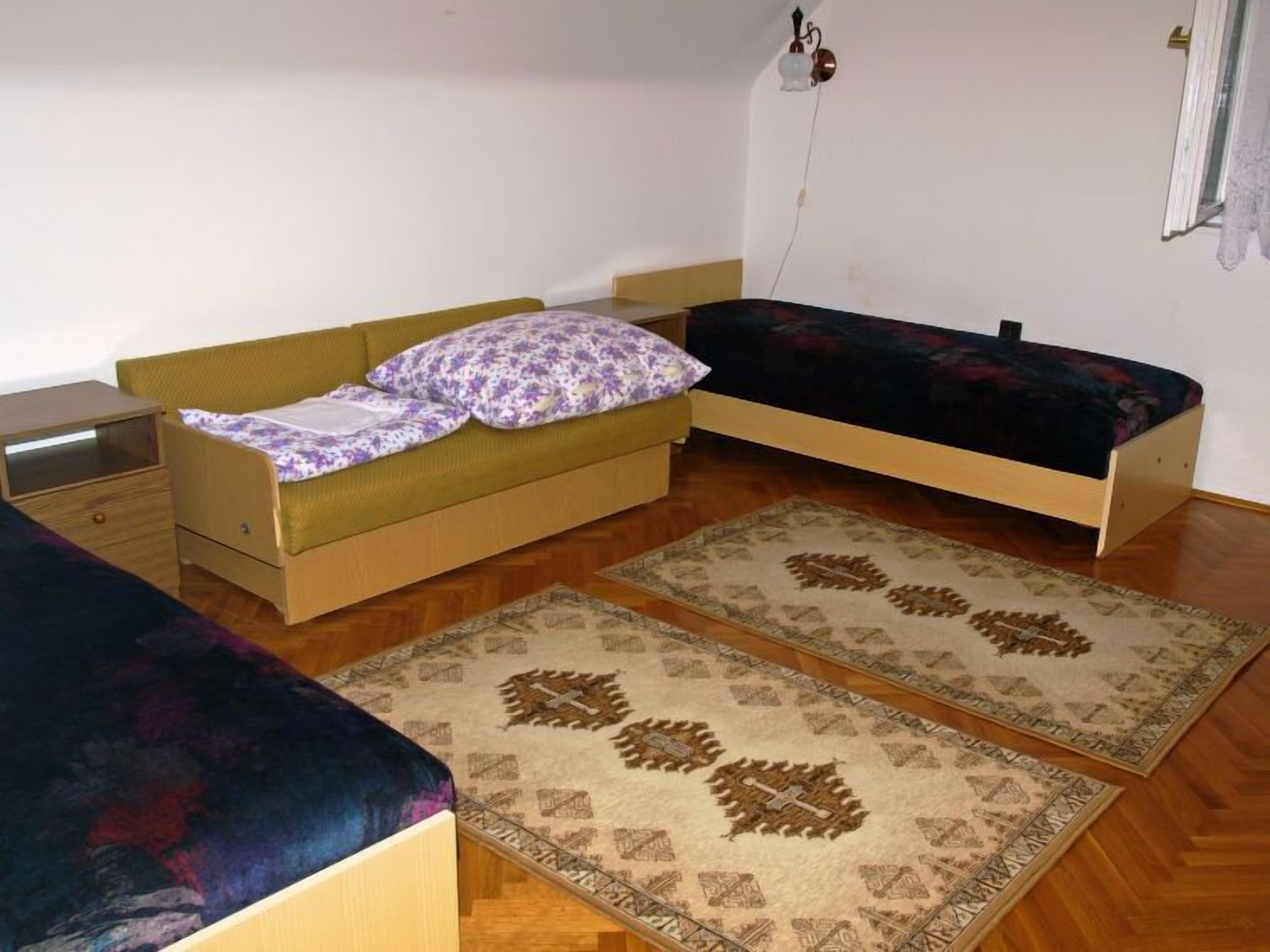 A small, single-room accommodation with a bed, a nightstand, and a window.