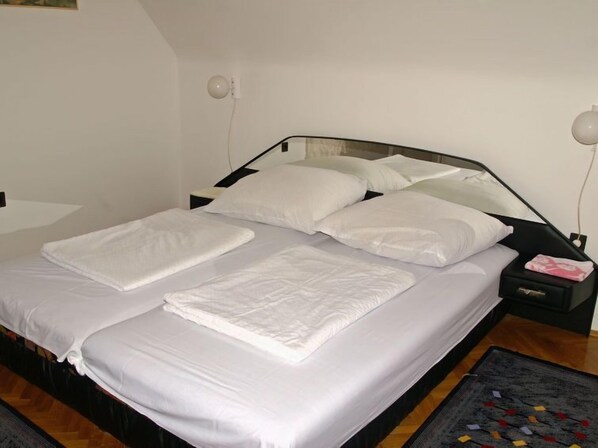 Una cama bien hecha con sábanas blancas en una habitación de diseño moderno y sencillo.