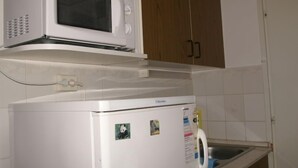 Une cuisine de taille réduite, équipée d’un four à micro-ondes et d’un réfrigérateur.