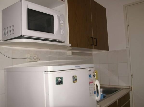 A compact kitchen with a microwave and a refrigerator.