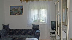 Un salon avec un canapé, un téléviseur, un meuble et un tableau accroché au mur.