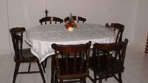 Une table à manger recouverte d’une nappe à motifs floraux, entourée de chaises en bois.