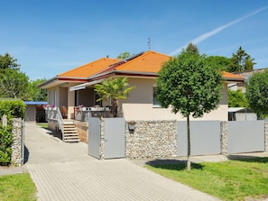 Una casa a due piani con tetto in tegole, un muro in pietra e un cancello in metallo.