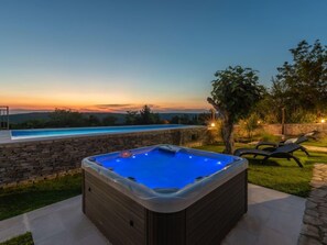 A hot tub with a stone wall and a pool, surrounded by grass and trees, during sunset. - Villa Ana Rita by Interhome (Rovinj/Kanfanar)