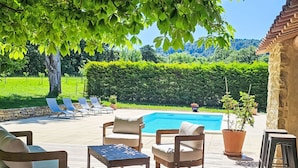Eine Holzterrasse mit Gartenmöbeln, einem Schwimmbad und Blick auf eine grüne Landschaft.