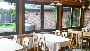 Un restaurante con paredes de ladrillo, amplios ventanales y mesas y sillas de madera.
