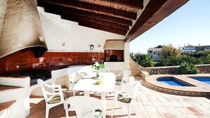 An outdoor patio with a stone wall, a built-in grill, a pool, and a table with chairs. - Els Pins by Interhome (Calpe/Calp)