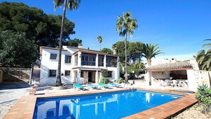 A two-story house with a swimming pool, surrounded by palm trees and a clear blue sky. - Els Pins by Interhome (Calpe/Calp)