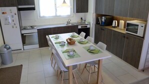Een moderne keuken met een eethoek, voorzien van een fornuis, oven, magnetron en spoelbak.