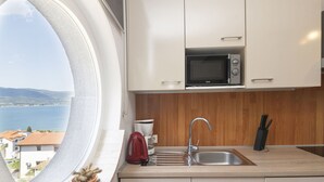 A kitchen with a view of the sea, a microwave, a sink, and a red kettle. - Apartment Anđa by Interhome (Trogir/Slatine)
