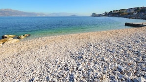 A pebble beach with clear water and distant mountains. - Apartment Anđa by Interhome (Trogir/Slatine)