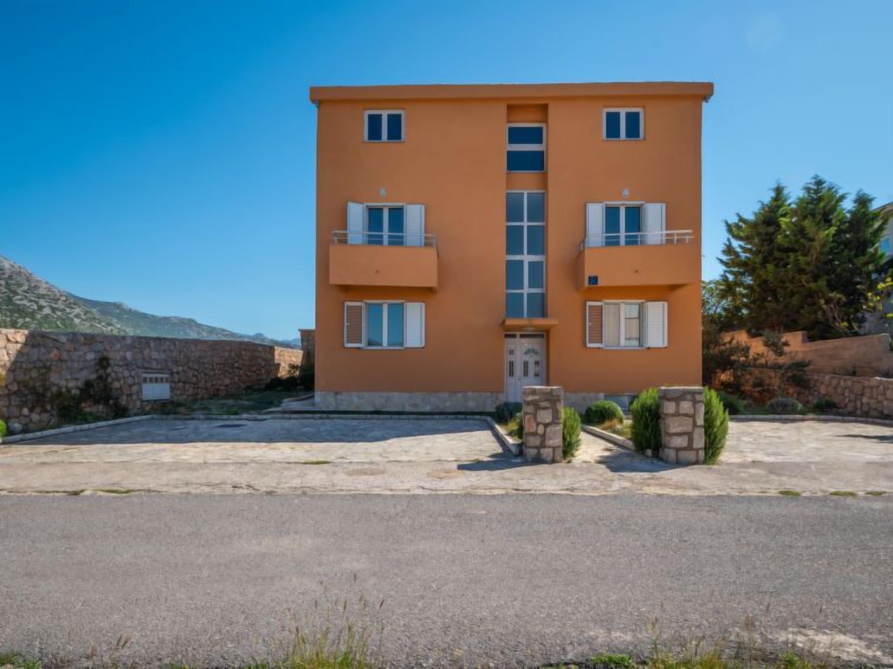 A two-story building with a central entrance, stone walls, and a paved courtyard.