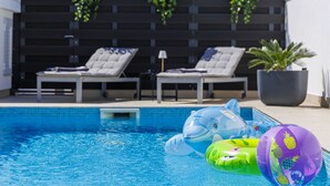 En swimmingpool med liggestole og oppustelige legetøj.