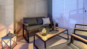 Hyggeligt udendørs siddeområde med sofa, sofabord og lygt.