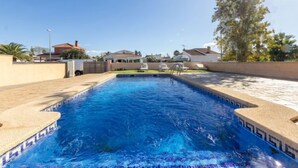 A rectangular swimming pool with a tiled edge, surrounded by a low wall and a paved deck. - Vacation home Alex by Interhome (Deltebre)
