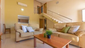 A spacious living room with a sofa set, a coffee table, and a staircase leading to an upper level. - Vacation home Alex by Interhome (Deltebre)
