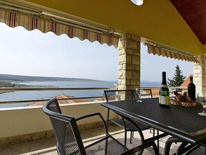 A balcony with a table, chairs, and a bottle of wine.