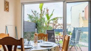 Ein Essbereich mit Tisch für zwei Personen, einem Stuhl und Blick auf den Garten durch eine Glastür.