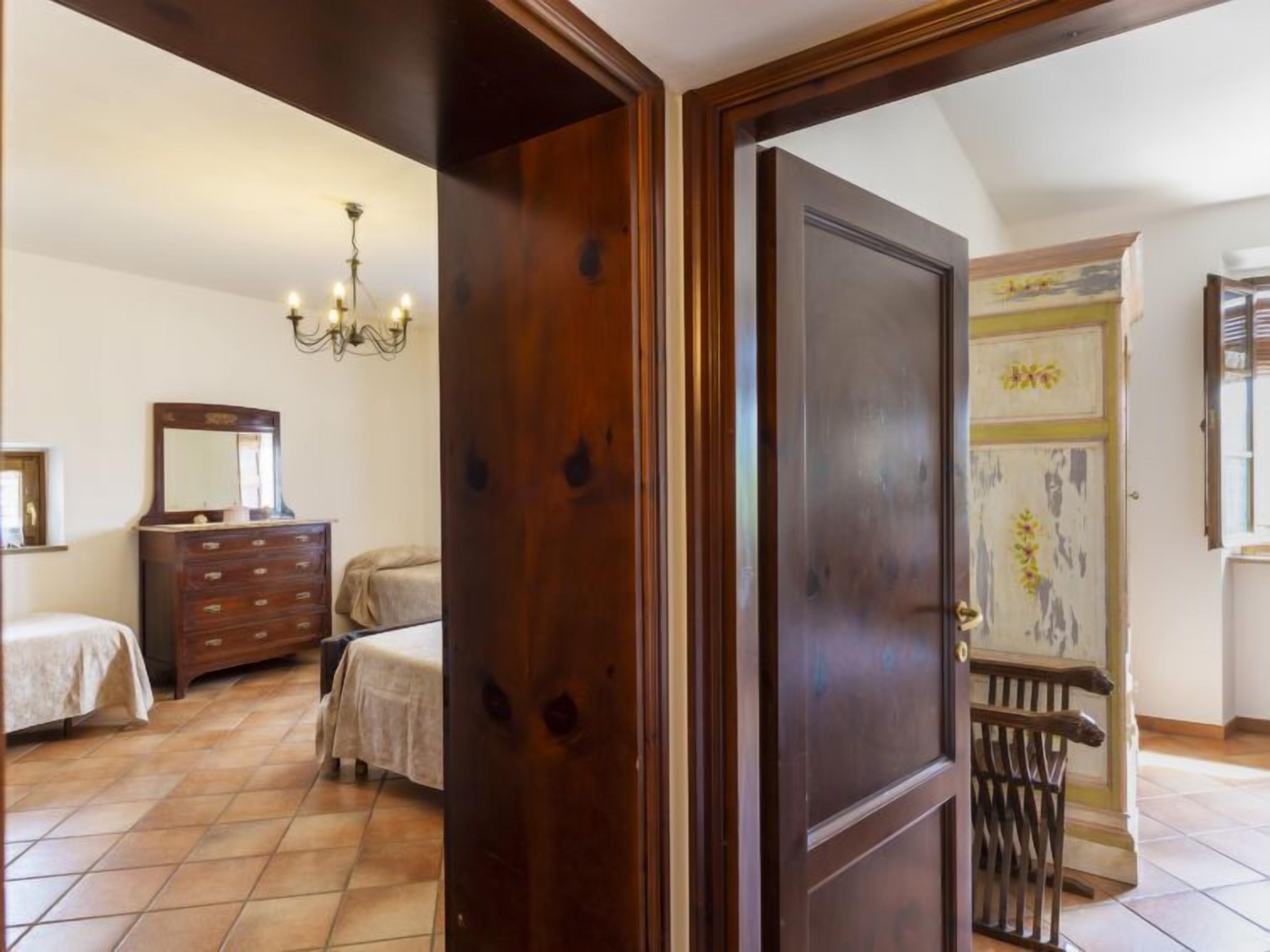 Een slaapkamer met een houten deur, een dressoir, een bed en een kroonluchter.