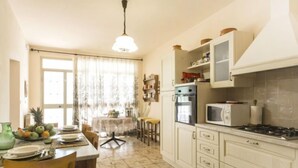 Une cuisine avec des meubles blancs, une cuisinière à gaz, un four à micro-ondes et un coin repas comprenant une table et des chaises.