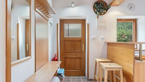 Un pasillo estrecho con un banco de madera, una puerta y un ventanal con vistas a la vegetación.