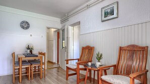 En matplats med ett träbord och stolar, en klocka på väggen och en inramad tavla ovanför bordet.