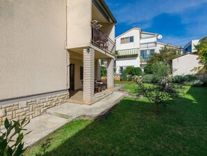 A residential building with a covered outdoor seating area, a stone pathway, and a well-maintained garden. - Apartment Zrinka by Interhome (Porec)