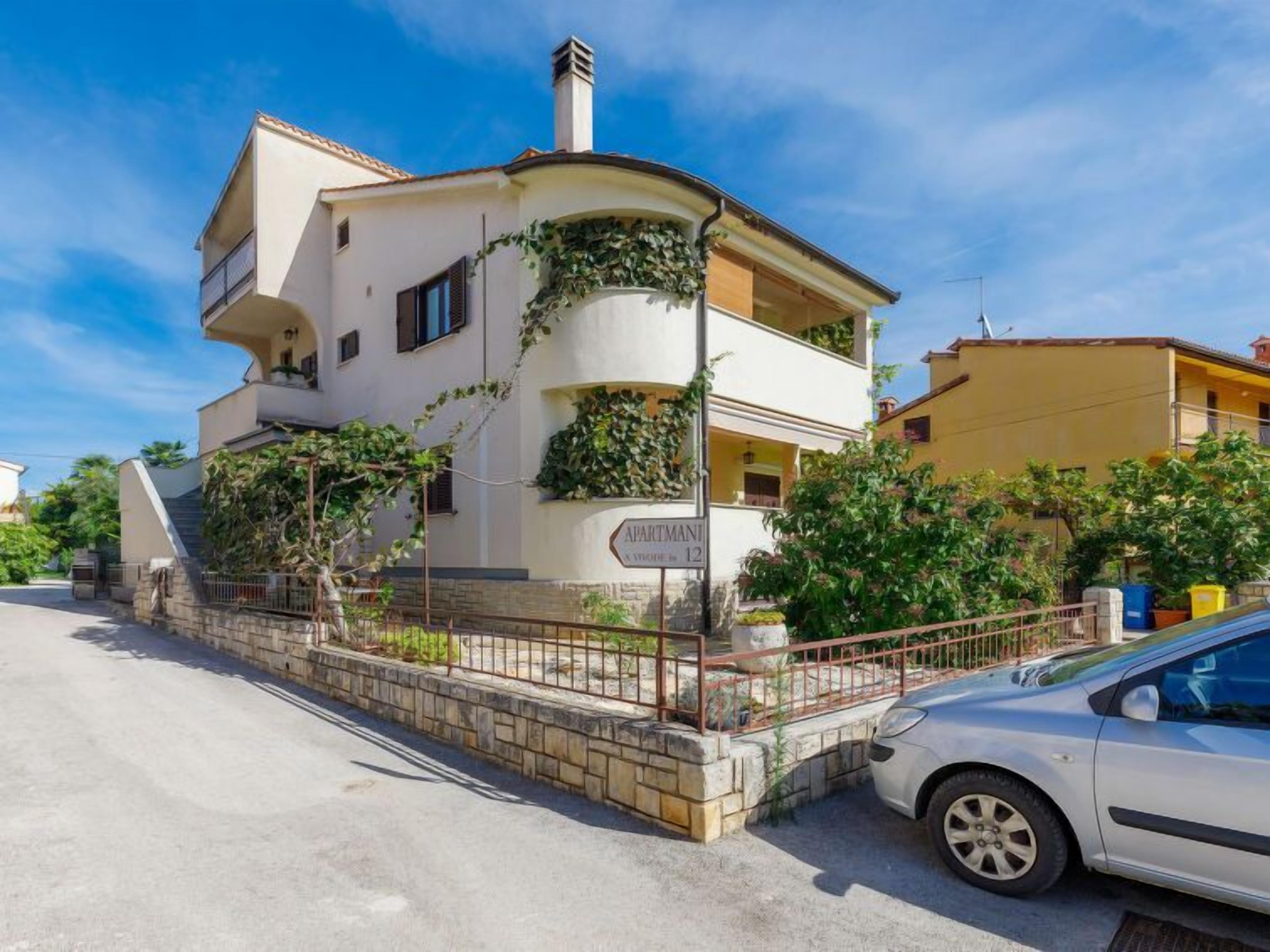 Un bâtiment à deux étages doté d’un balcon, d’une enseigne indiquant « AURITMANI » et d’une voiture gar ée.