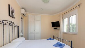 A bedroom with a bed, a TV, and a window.