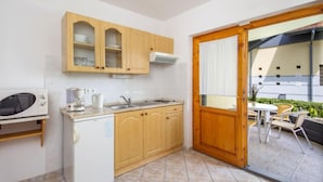 Cocina compacta con armarios de madera, un microondas y un lavamanos.