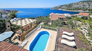 Un complexe hôtelier doté d’une piscine, de chaises longues et offrant une vue sur la mer.