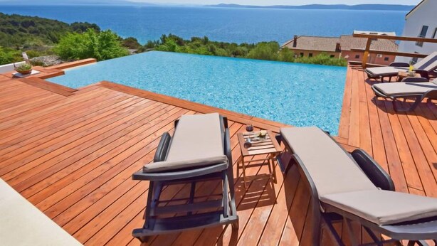 A wooden deck with lounge chairs and a pool overlooking a scenic ocean view. - Vacation home Andrea by Interhome (Trogir/Okrug Gornji)