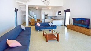 A modern living room with a blue sofa, a glass coffee table, and a TV on a wooden stand. - Vacation home Andrea by Interhome (Trogir/Okrug Gornji)