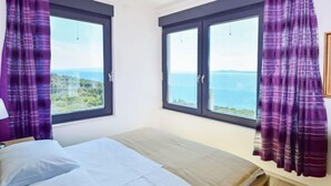 A bedroom with a bed, a nightstand, and a window with curtains. - Vacation home Andrea by Interhome (Trogir/Okrug Gornji)