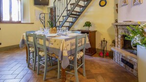 A dining area with a table set for four, a wooden staircase, and a fireplace. - San Lorenzo by Interhome (Gambassi Terme)