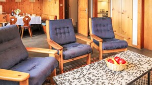 A cozy room with wooden walls and furniture, including two armchairs and a table with a basket of fruit. - Vacation home Mungg by Interhome (Nendaz)