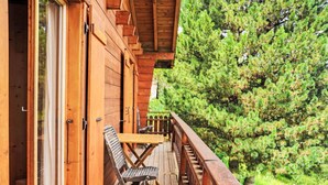 A wooden deck with a table and chairs, overlooking a dense forest. - Vacation home Mungg by Interhome (Nendaz)