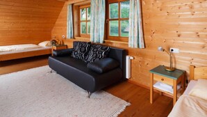 Ein gemütliches Blockhausszimmer mit einer Couch, einem kleinen Tisch und einem Fenster mit Vorhängen.