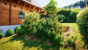 Ein Holzhaus mit gepflegtem Garten und freiem Blick auf die umliegenden Hügel.