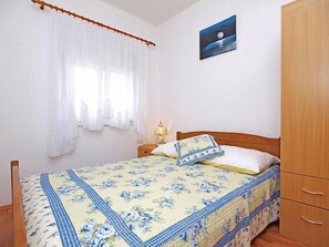 A bedroom with a bed, a nightstand, a lamp, a wardrobe, and a painting on the wall. - Apartment Sofija by Interhome (Trogir/Slatine)