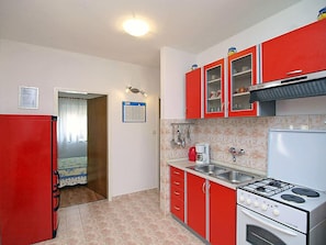 Une cuisine de taille réduite avec des placards rouges, une cuisinière blanche et un évier.