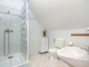 Ein Badezimmer mit Duschkabine, Toilette, Waschbecken und Schrank.