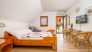 Ein Schlafzimmer mit einem hölzernen Bett, einem kleinen Tisch mit Stühlen, einem Fernseher und einem Balkon mit Blick.
