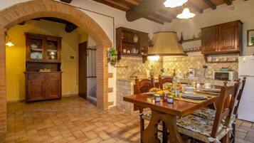 Una cucina rustica con travi a vista, un arco in mattoni, mobili in legno e un'area pranzo con tavolo e sedie.