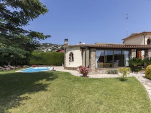 A villa with a swimming pool, stone walls, and a garden.