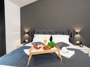 En pænt redt seng med et bakke med morgenmad, herunder jordbær, en croissant og et glas juice.