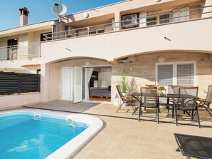 Ein Wohnhaus mit Schwimmbad, Sitzgelegenheiten im Freien und einer überdachten Terrasse.