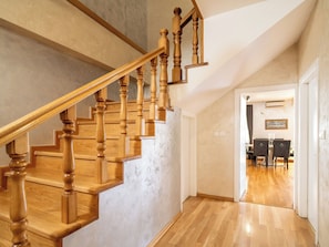 A wooden staircase with a handrail leading to a dining area.